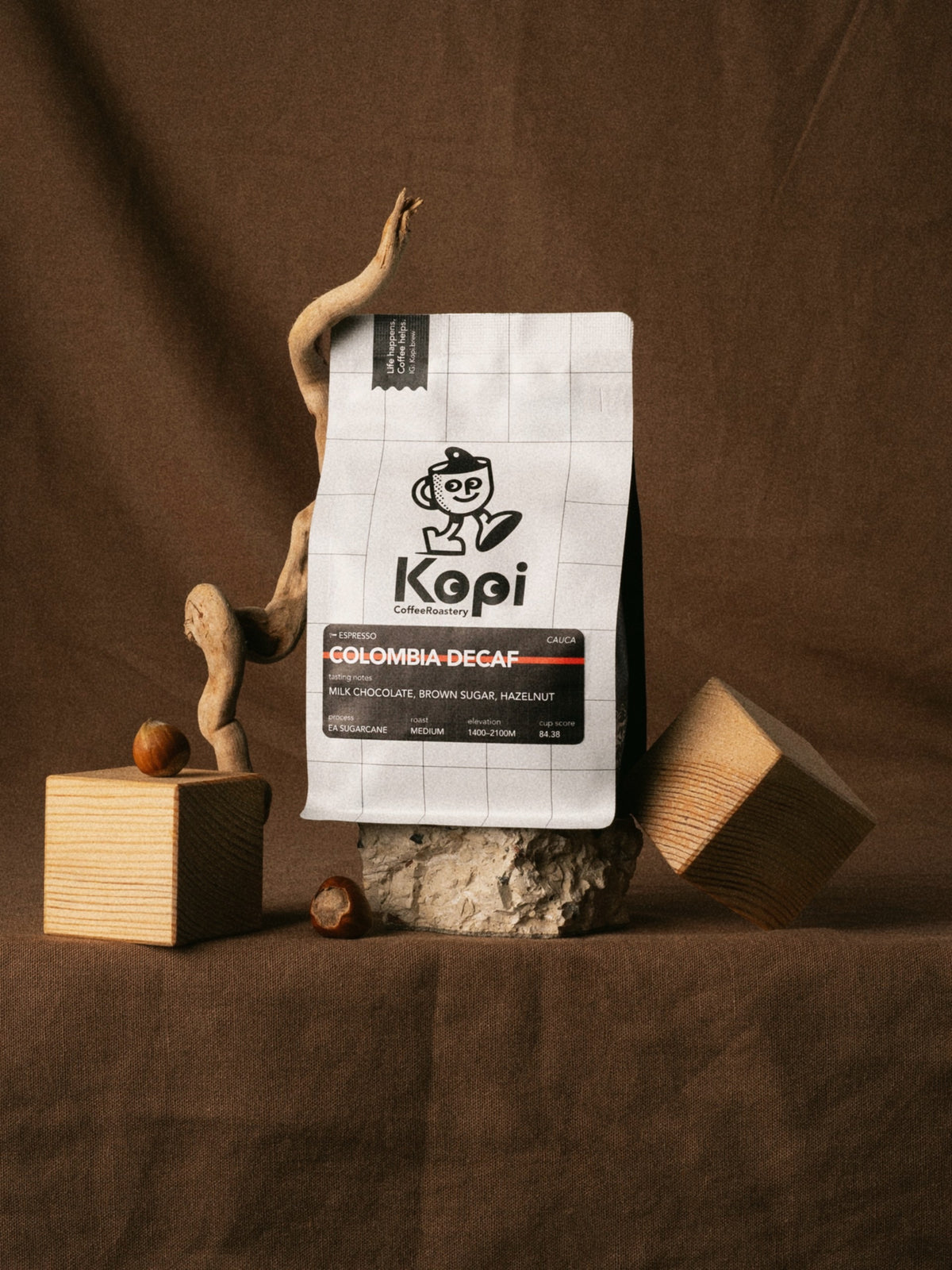 KOPI Colombia decaf coffee bag in a warm brown display with dried botanicals.