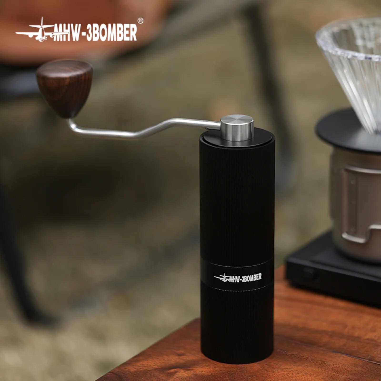 Black manual coffee grinder with 'MHW-3BOMBER' branding on a wooden surface.