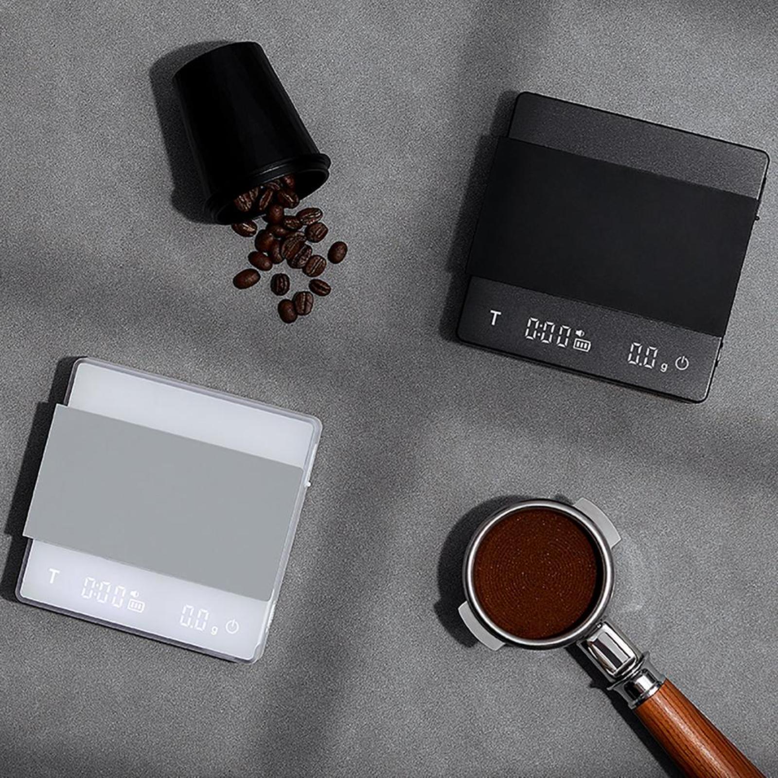 Digital coffee scales with coffee beans and a coffee scoop on a gray surface