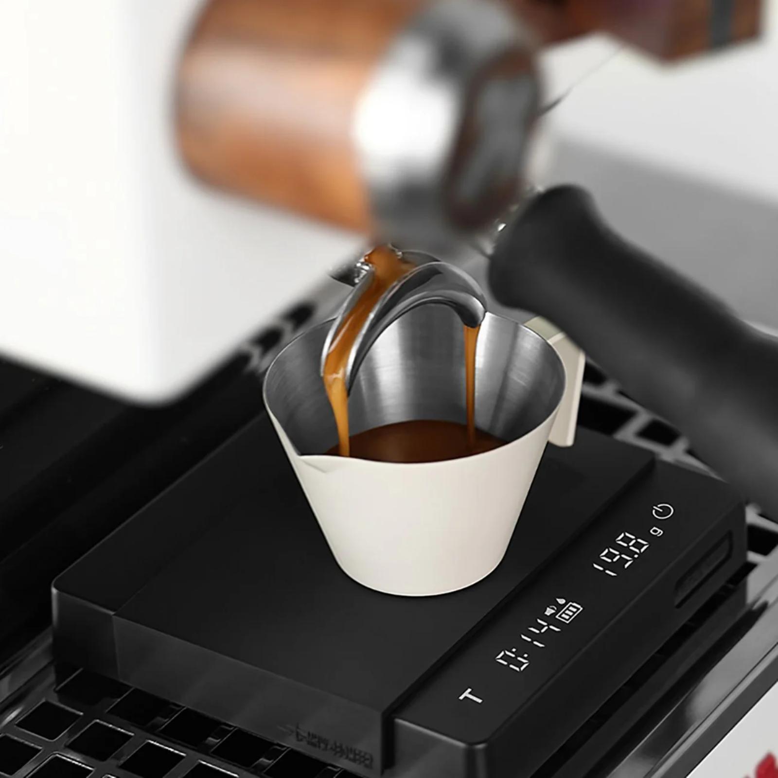 Espresso being poured from a portafilter into a white cup on a digital scale.