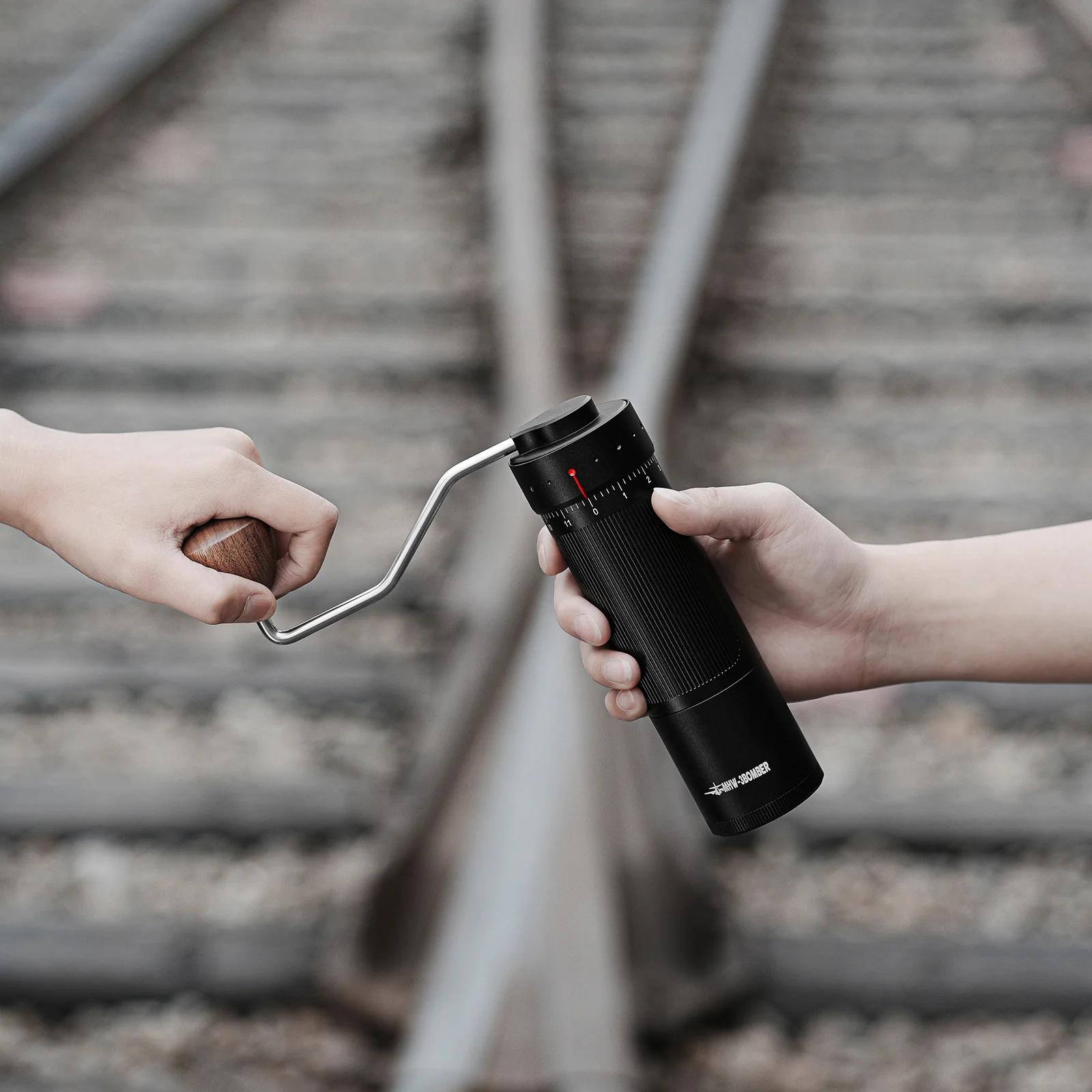 Two hands with a coffee grinder and a stone on railway tracks