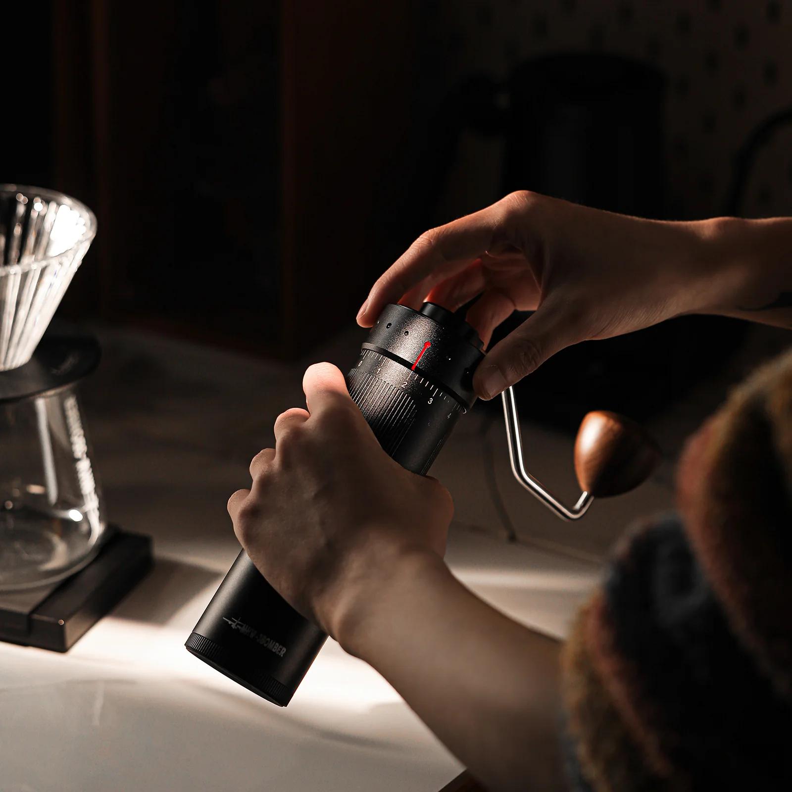 Person using a coffee grinder with a dark background
